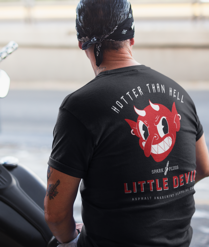 
                  
                    Little Devil Tee from Asphalt Anarchist Clothing Co. Black soft-style tee worn by an old-school biker posted on a Harley chopper. Retro devil head graphic and the slogan “Hotter Than Hell” blaze across the chest, echoing the gritty spirit of roadside garages and outlaw chrome. AI Generated image.
                  
                
